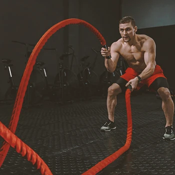 A buff male working out with battle ropes