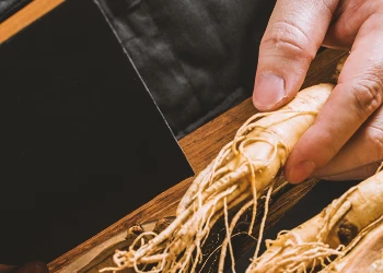 A chef holding Korean ginseng at a table