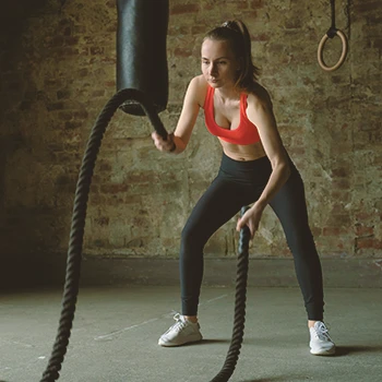 A person at the gym working out with two battle ropes