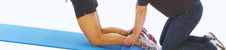 A coach helping a person do nordic hamstring curls
