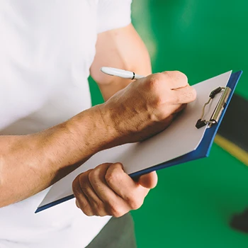 A gym coach writing down on a clipboard at a gym
