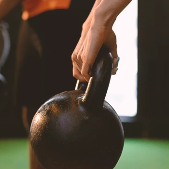 A person lifting up a kettlebell with a firm grip