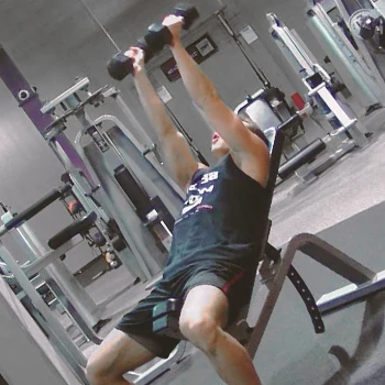 A person doing incline dumbbell tricep extensions at the gym