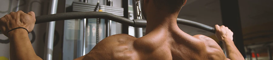 A person on a machine at the gym doing lat pulldowns