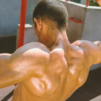 A person with good trap and back muscles flexing outside