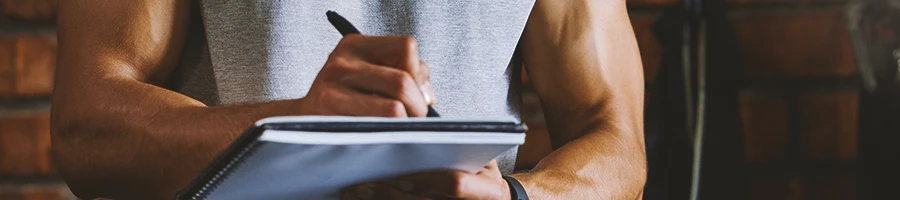 A gym coach writing down on a clipboard at the gym