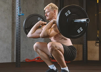 A person working out with pause squats at the gym