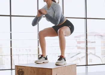 A woman doing cardio with box jumps at the gym