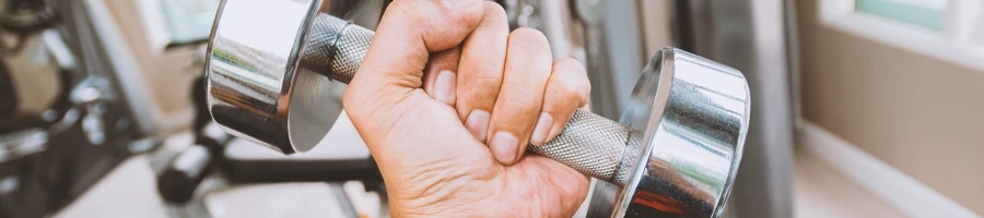 A person holding a dumbbell at the gym to increase grip strength