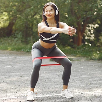 A woman doing squats while using a resistance band