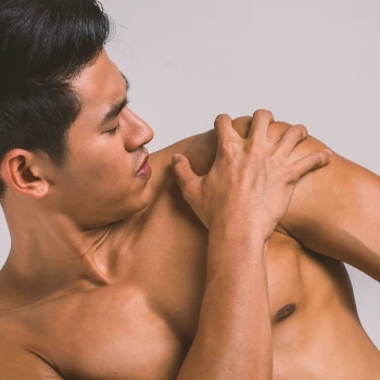 A male applying cream on his shoulders