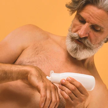 An old male pouring cream on his hand