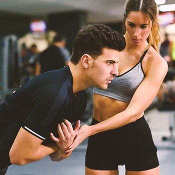 A gym coach helping a person workout at the gym