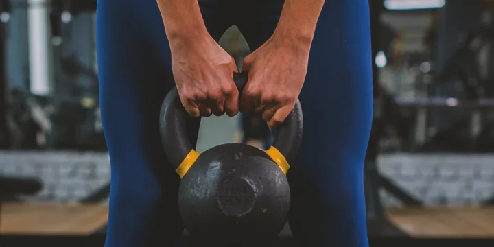 A person doing workouts with a kettlebell in the gym