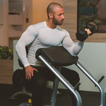 A person doing preacher curls at the gym