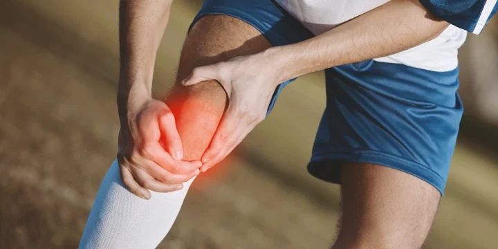 A person holding his arthritic knee outside