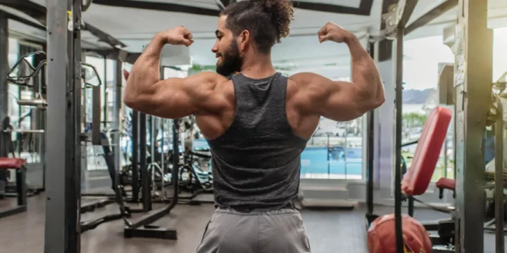 A man in the gym flexing his back and bicep muscles