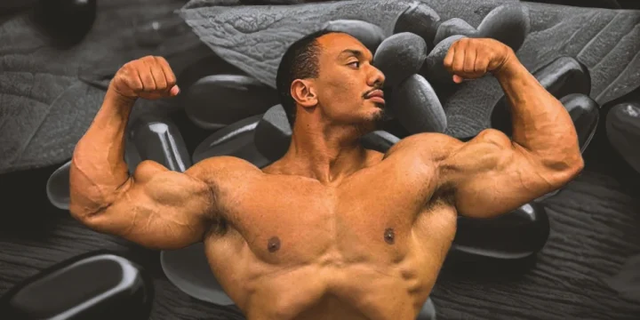 Larry Wheels posing his muscles in front of supplements