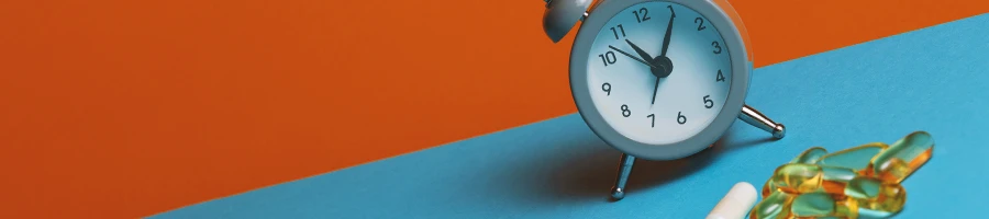 A clock on a table with supplements on the side