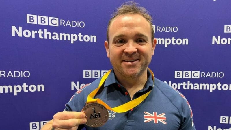 Jonny Ball holding his weightlifting medal