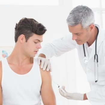 A muscular man having an injection from his doctor