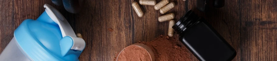 A top view of supplements, a tumbler, and protein powder