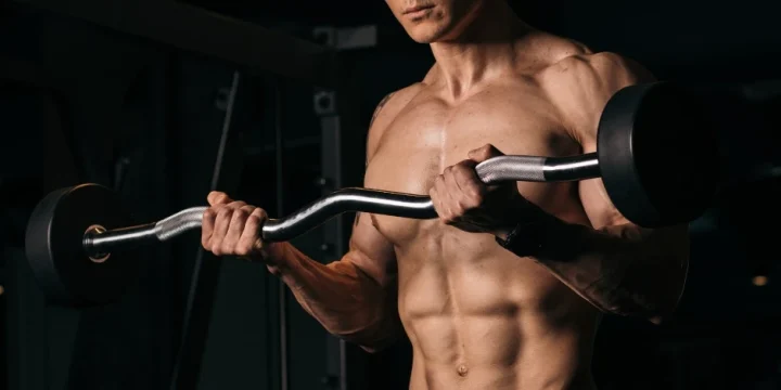 A muscular man using a barbell in his workout