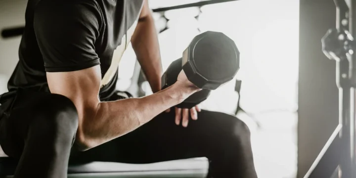 A guy doing dumbbell curls in the gym