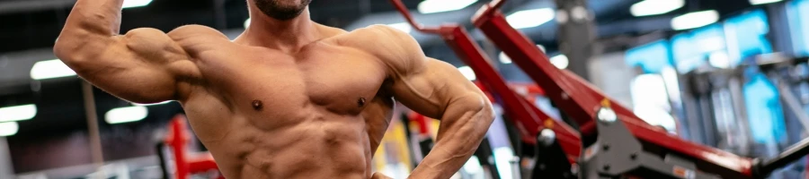 A muscular guy in the gym showing off his muscles
