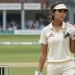 A hot female cricket player holding a bat in the cricket field