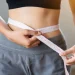 A woman using a measuring tape after losing weight fast